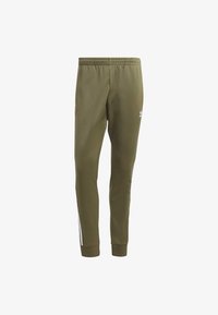 Olivgröna träningsbyxor med avsmalnande passform, elastisk midja och vita sidoremsor. Har ribbstickade muddar och en liten logga på sidan.