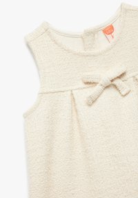Vestido sin mangas de color crema, texturizado, con escote redondo, detalle de lazo en la parte delantera y plisados debajo de la cintura para mayor forma.