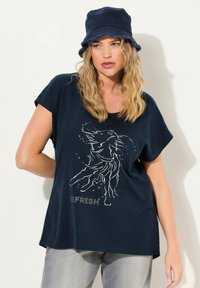 Námořnická modrá tričko s krátkým rukávem, má bílé abstraktní grafické provedení a pod ním je vytištěn nápis "REFRESH". Měkká látka s uvolněným střihem.