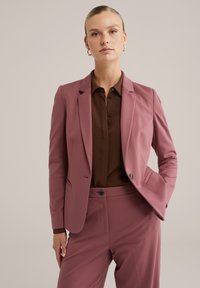 Rosa maßgeschneiderte Blazer aus glattem Stoff, mit Reverskragen, Ein-Knopf-Verschluss und seitlichen Taschen, kombiniert mit einem braunen Hemd.
