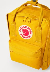 Κίτρινο σακίδιο πλάτης Fjällräven Kånken με ορθογώνιο σχήμα, που διαθέτει μεγάλη μπροστινή τσέπη, λογότυπο επωνυμίας και διπλούς ζιπέρ.