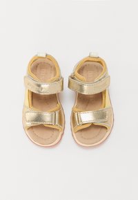 Złote metaliczne sandały z żółtymi akcentami z tkaniny, z dwiema regulowanymi rzepami, wyściełaną wkładką i gumową podeszwą.