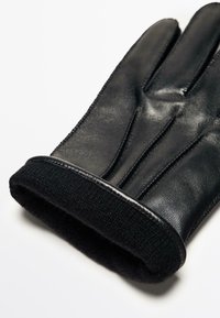 Guanto in pelle nera con finitura liscia, caratterizzato da un morbido polsino in maglia nera. Il design include dita strutturate e dettagli di cucitura sottili.