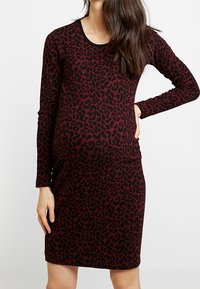 Abito premaman a maniche lunghe in bordeaux con stampa leopardata nera. Vestibilità slim, scollatura rotonda e tessuto elasticizzato. Design al ginocchio.