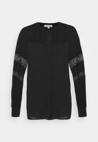 Schwarze Bluse mit langen Ärmeln und Spitzenpaneelen, Knopfleiste und gefalteten Details an den Schultern. Aus glattem Stoff gefertigt.