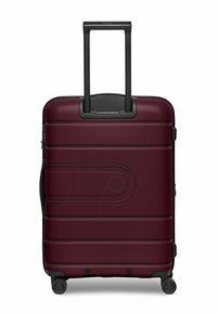 Valigia bordeaux con superficie strutturata, manico retrattile nero e quattro ruote. Presenta scanalature orizzontali e un dettaglio circolare sul davanti.