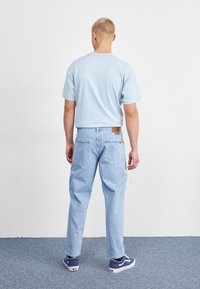T-shirt en coton bleu clair, coupe ample, manches courtes ; jeans en denim bleu clair, style décontracté, dotés de poches arrière et d'une étiquette en cuir.