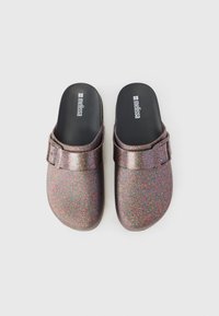 Glittery purple clogs with a black interior, featuring a single adjustable strap and a smooth, shiny texture.