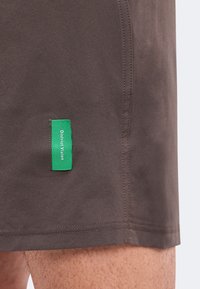 Short brun en gros plan montrant une étiquette en tissu verte avec un texte blanc indiquant "Digital Vision" près de l'ourlet.