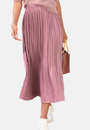 Faltenrock in Midilänge aus hellrosa Stoff mit elastischem Bund. Kombiniert mit weißen Sneakern und einer braunen Handtasche.