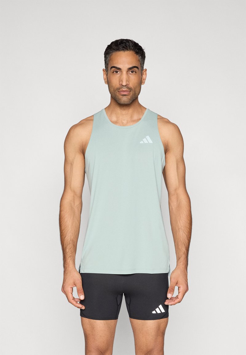 Šviesiai žalia be rankovių sportinė liemenė su apvalia iškirpte, pagaminta iš lygios medžiagos; ant kairiojo krūtinės regiono yra baltas Adidas logotipas. Juodi sportiniai šortai.