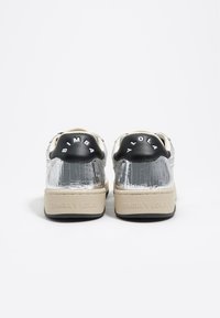 Silver cracked leather sneakers with black heel accents, white branding, and beige soles. Flat design with a textured surface detail.