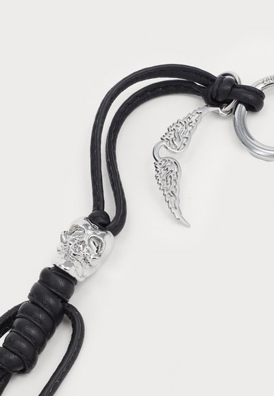 Breloc din piele neagră, decorat cu un charm în formă de craniu argintiu cu detalii intricate, și un accent în formă de aripă argintie atașat la un inel metalic.
