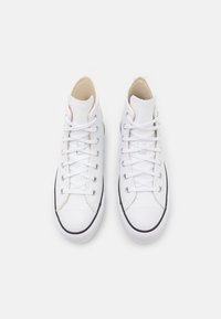 Zapatillas altas blancas con una parte superior de cuero liso, lengüeta de lona, suela de goma negra y un sistema de cordones clásico con ojales plateados.