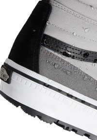 Primer plano del talón de una zapatilla Vans gris y negra con gotas de agua en la tela y la suela de goma.