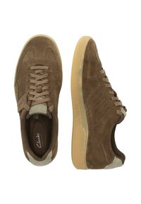 Bruna mockaskor med en mjuk textur, som har en sula av gummiregummis, snörning, vadderad krage och diskreta sömdetaljer.