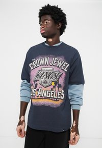 Hanorac bleumarin cu un imprimeu grafic care prezintă "Crown Jewel Kings Los Angeles." Mâneci lungi albastre; croială lejeră; textură moale.