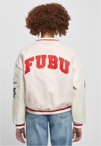 FUBU bomberjakke med rosa kropp og hvite ermer, med iøynefallende røde bokstaver og ribbestrikkede mansjetter. Merkbare grafikker på ermene.