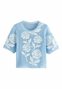 Lyseblå strikket sweater med et blomstret hvidt mønster, bølget halsudskæring og korte ærmer, med et løst, tekstureret design.