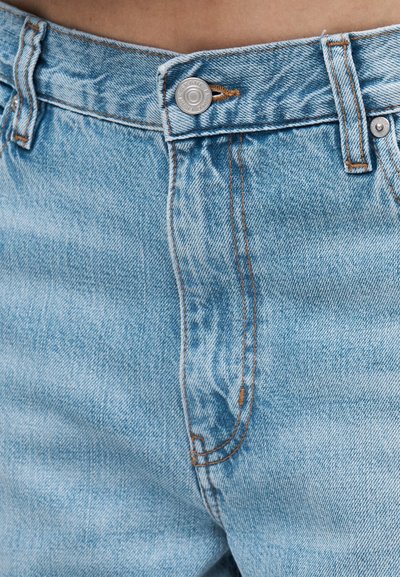 Ανοιχτό μπλε τζιν υφάσματος denim με μεταλλικό κουμπί και ραμμένο με πορτοκαλί κλωστή στη μέση και στο φερμουάρ.