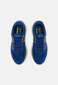 Des chaussures de sport bleues avec une tige en mesh et des accents de logo, dotées d'une semelle rembourrée dans des tons de bleu et jaune, et d'une surface texturée.