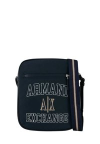 Borsa a tracolla blu navy con testo del logo bianco e metallico. Presenta una tasca con zip e una tracolla regolabile a righe. Texture liscia.