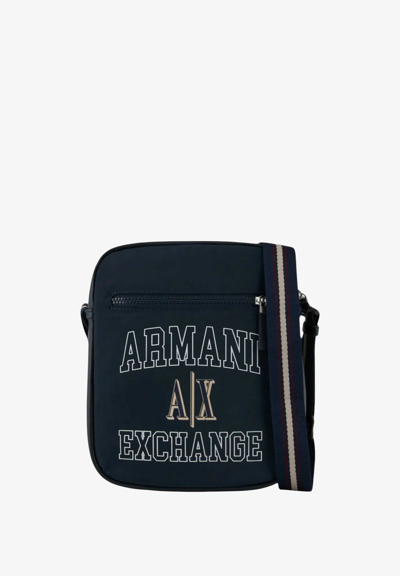 Borsa a tracolla blu navy con testo del logo bianco e metallico. Presenta una tasca con zip e una tracolla regolabile a righe. Texture liscia.
