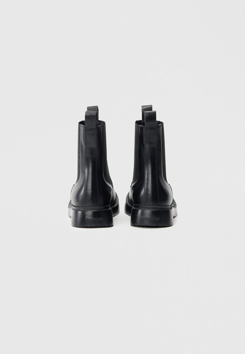 Svarta läderstövletter med slät yta, elastiska sidor och dragflikar. Har en flat gummisula. Bakifrån.