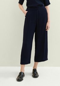 Námořnické široké kalhoty z texturované látky s elastickým pasem a šňůrkou. V kombinaci s černými šněrovacími botami.