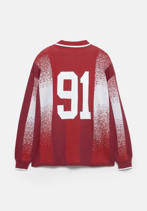 Maglioncino rosso con colletto a strisce bianche, motivi bianchi sfumati e grande '91' bianco stampato sulla schiena.