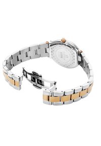Reloj de acero inoxidable con una correa acentuada en dorado, caja octagonal y fondo texturizado plateado. Cuenta con un broche de botón a presión.