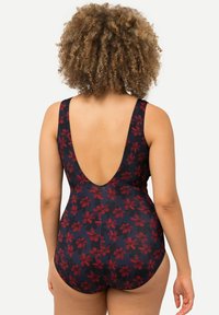 Maillot de bain une pièce bleu marine à motif floral rouge ; dos plongeant, bretelles larges et texture de tissu lisse.
