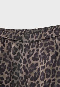 Gros plan sur un tissu à imprimé léopard gris foncé et noir avec une ceinture cousue et des plis.