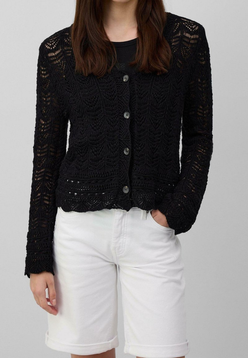 Black knitted cardigan with long sleeves, featuring a delicate lace pattern, five buttons down the front, rounded hem, and textured fabric.