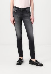 Vaqueros de mezclilla negra con corte slim, diseño de cinco bolsillos y un ligero desvanecimiento. Combinados con mocasines negros, que destacan una textura suave.