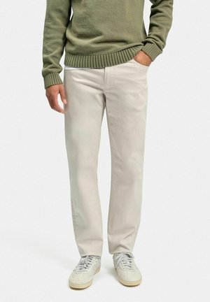 Lette beige chinos med lige pasform, lavet af blødt bomuldsstof. Blandet med en grøn strikket sweater og lysegrå sneakers.