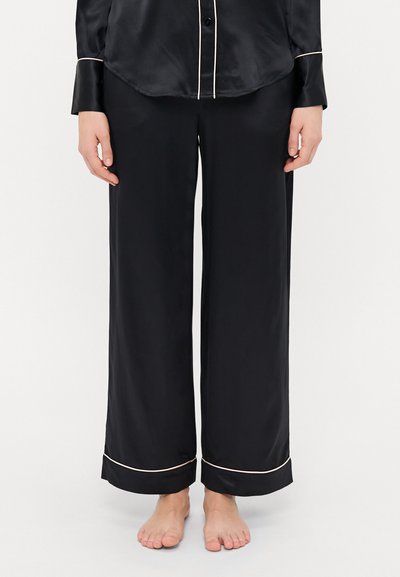Schwarze Satin-Pyjama-Hosen mit weit geschnittenem Design und einem kontrastierenden hellen Besatz am Saum. Sanfte Textur, lockere Passform.