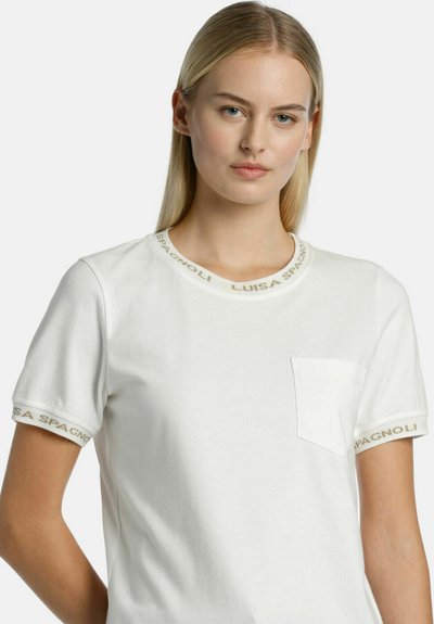 Tricou alb cu mânecă scurtă și guler rotund, având numele brandului brodat cu fir auriu pe guler și manșete. Detaliu cu buzunar frontal.