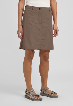 Brown, knee-length skirt made of lightweight fabric, featuring a front button closure and two side pockets. Paired with patterned sandals.
