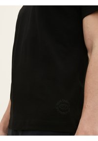 Black cotton t-shirt with a crew neck, short sleeves, and a subtle logo at the hem. Smooth texture, straight fit.