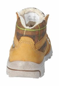 Bota de invierno marrón y amarilla para niño con forro de piel sintética y detalle de tela de cuadros, vista desde la parte trasera.