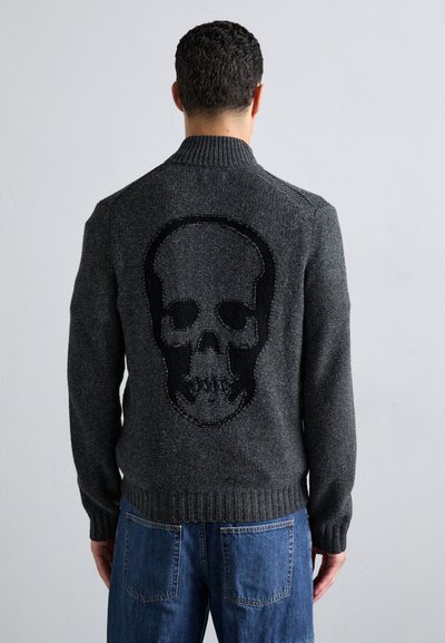 Cardigan gris tricoté avec un grand design de crâne noir dans le dos. Il possède un col et des poignets côtelés, avec une finition texturée.