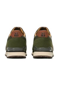 Sneaker in suede verde e marrone con accenti neri del logo, colletto imbottito e suole in gomma beige, caratterizzate da un motivo di battistrada robusto.