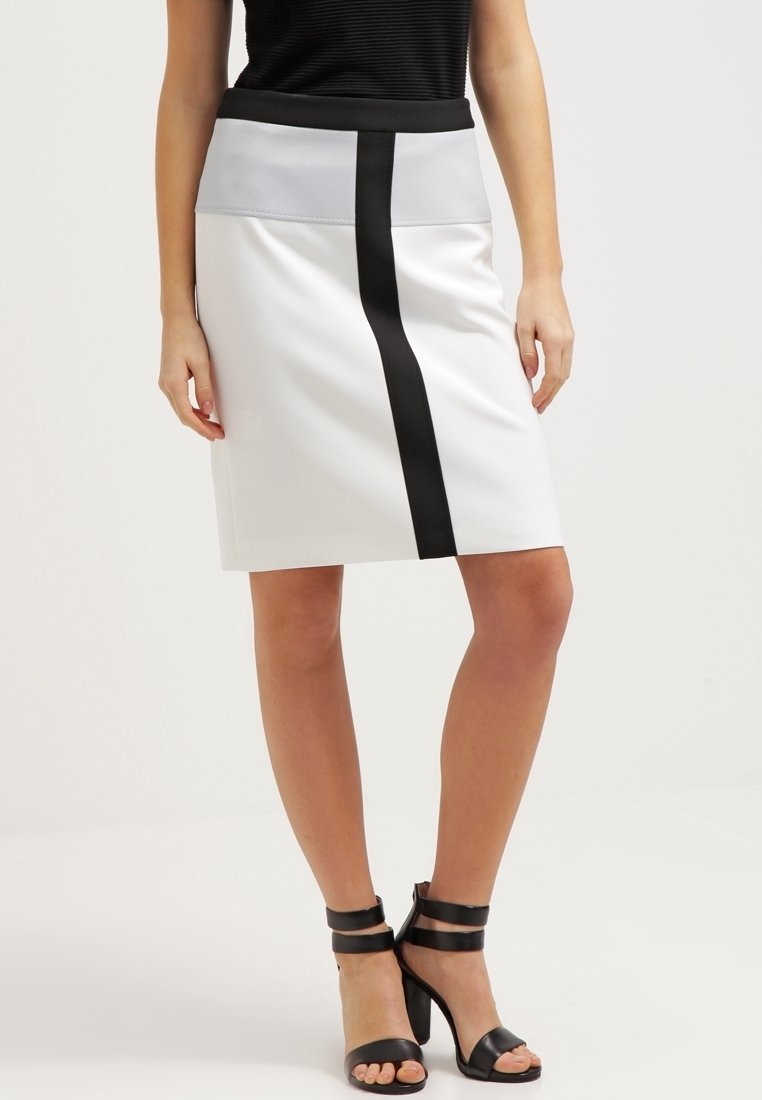 Bílá sukně s přiléhavým střihem, zdobená černým vertikálním pruhm a šedým pasem. Hladká textura; v kombinaci s černými sandály na vysokém podpatku.