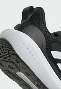 Scarpa sportiva nera con tomaia in maglia testurizzata, suola bianca ammortizzata etichettata "CLOUDFOAM" e suola in gomma nera con motivo a battistrada.