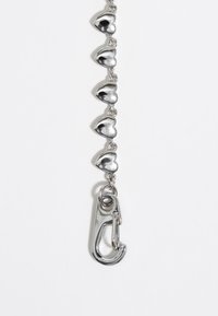 Cadena de plata con cinco eslabones en forma de corazón brillante y un cierre tipo clip. Los corazones son reflectantes, creando una textura metálica suave.