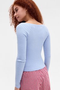 Top lung cu maneci lungi de culoare albastru deschis, cu un decolteu larg, design ajustat și textură moale, asortat cu pantaloni cu model gingham roșu și alb.