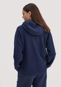 Marineblaue Fleece-Hoodie mit Kapuze, weichem Material und lässigem Schnitt. Mit gerippten Bündchen und abgerundetem Saum, kombiniert mit passenden Hosen.
