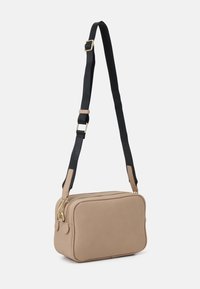 Borsa a tracolla in pelle marrone chiaro con superficie texture, zipper dorato e tracolla nera regolabile con un accento beige vicino al gancio.