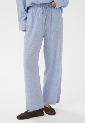 Sinised ja valged triibulised, mugavalt lõhkuvad püksid elastse vöö ja paelaga, valmistatud kergest kangast, kombineeritud pruunide seemisnahast kingadega.